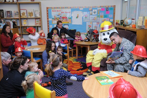 Airman 1st Class Zachary Torres, 341st Civil Engineer Squadron member, and Sparky the Fire Dog, read a storybook to children at the Malmstrom Air Force Base Library on Oct. 8 in celebration of Fire Prevention Week, which ran from Oct. 6 to 12. The theme this year was preventing kitchen fires. (U.S. Air Force photo/Senior Airman Katrina Heikkinen)