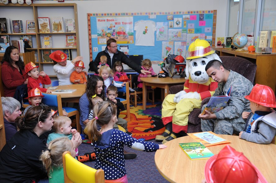 Airman 1st Class Zachary Torres, 341st Civil Engineer Squadron member, and Sparky the Fire Dog, read a storybook to children at the Malmstrom Air Force Base Library on Oct. 8 in celebration of Fire Prevention Week, which ran from Oct. 6 to 12. The theme this year was preventing kitchen fires. (U.S. Air Force photo/Senior Airman Katrina Heikkinen)
