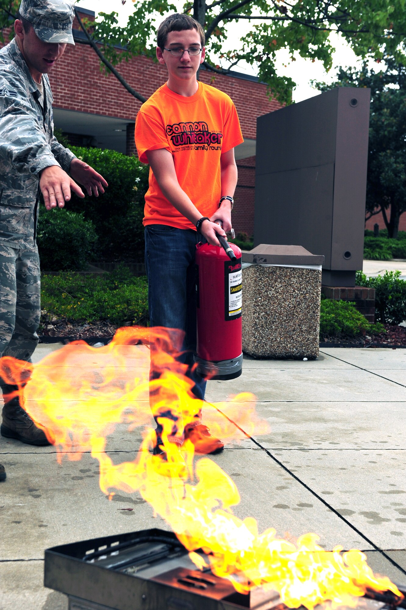 U.S. Air Force Airman 1st Class Michael Gilligan, 4th Civil Engineer Squadron firefighter, teaches a teen the proper way to use a fire extinguisher at Seymour Johnson Air Force Base, N.C. Oct. 11, 2013.   Firefighters helped raise awareness during Fire Prevention Week by instructing commissary visitors on how to use safety equipment.  (U.S. Air Force photo by Airman 1st Class Brittain Crolley)