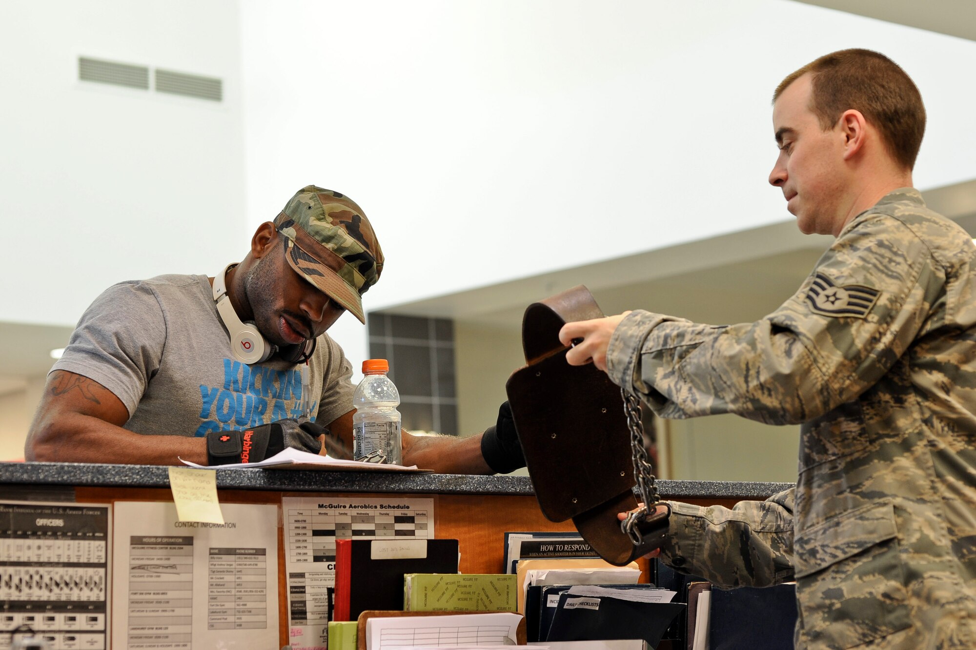 Staff Sgt. Michael Brockington signs out a lifting belt from Sgt. Jordan Beatty, 87th Force Support Squadron fitness specialist Oct. 15, 2013, at the McGuire Fitness and Sports Center. The fitness center is open till midnight every day for ease of access to its many patrons. (U.S. Air Force photo by Airman 1st Class Ryan Throneberry/Released)