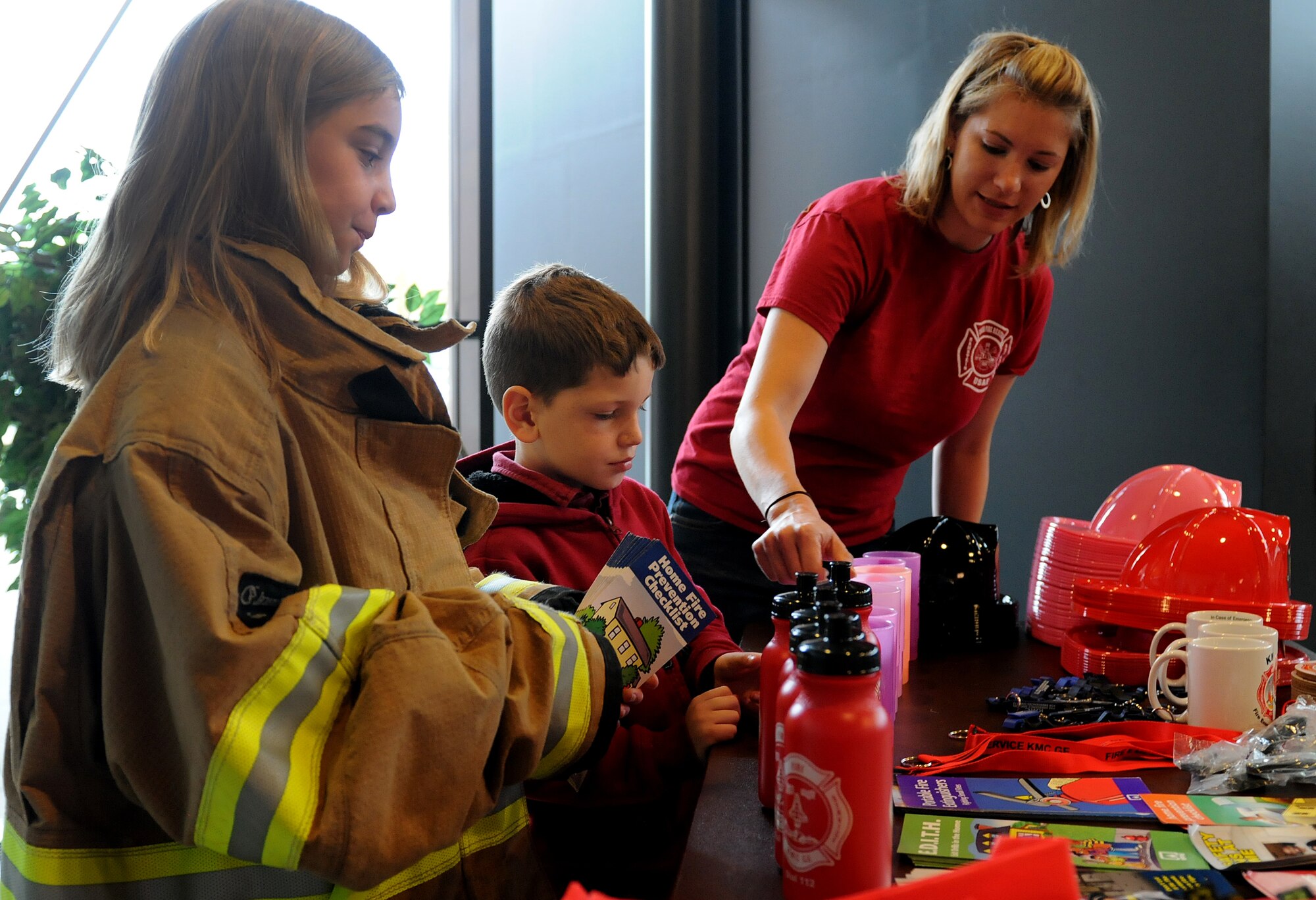 (From left to right) Hailey, Colton and Jenna Ratlief, family of Senior Airman James Ratlief, 86th Civil Engineer Squadron firefighter, set up souvenirs during Fire Prevention Week, Oct. 11, 2013, Ramstein Air Base, Germany.  Sparky the fire dog and KMC firefighters held briefings and conducted live fire extinguisher training at KMC elementary schools, the Ramstein Express gas station and Enlisted Club. (U.S. Air Force photo/Airman 1st Class Holly Mansfield)