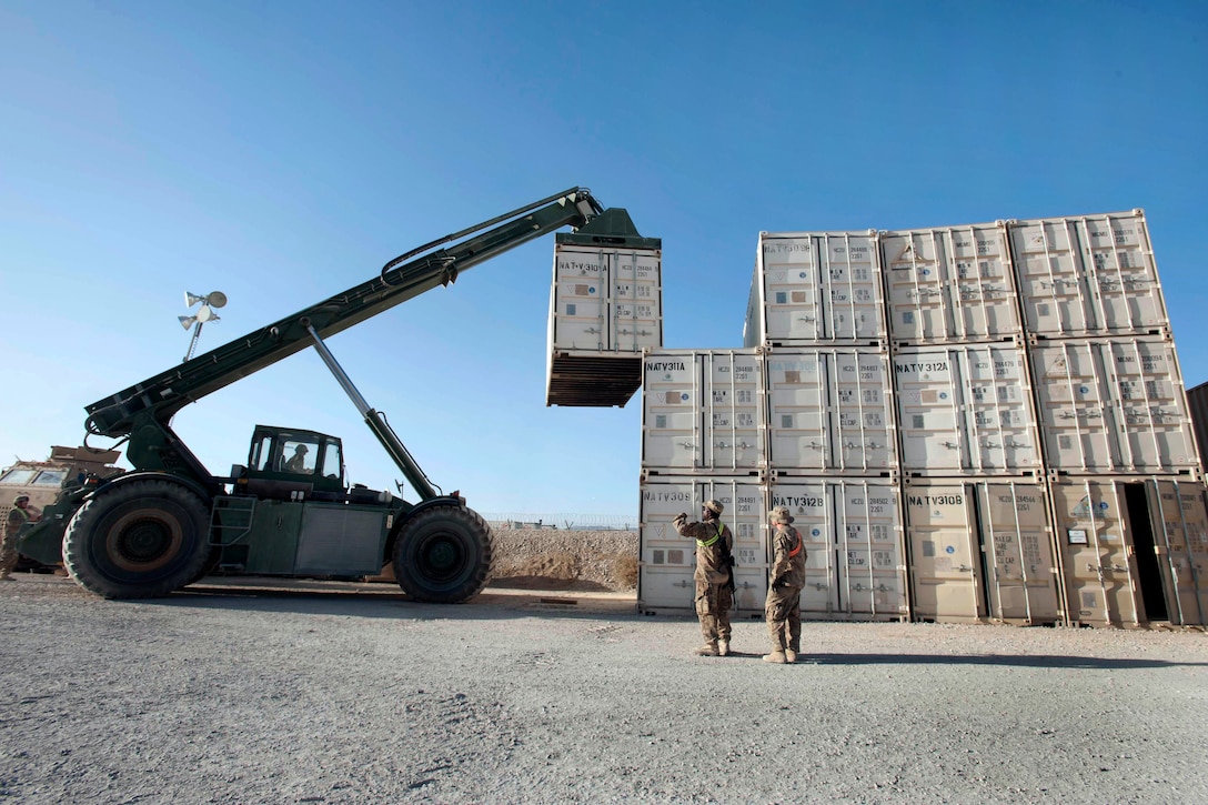 U.S. Army Staff Sgt. Adam Holen operates a handler to move containers with guidance from soldiers on Kandahar Airfield, Afghanistan, Oct. 8, 2013. Holen is assigned to the South Dakota Army National Guard's 152nd Combat Sustainment Support Battalion and the soldiers are assigned to the Maryland Army National Guard's 1229th Transportation Company.