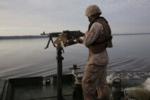 A Marine with Bridge Company, 8th Engineer Support Battalion, 2nd Marine Logistics Group provides security as they cross the New River with M1A1A1 Abrams Main Battle Tanks and M88 Hercules recovery vehicles from 2nd Tank Battalion, 2nd Marine Division during a tank crossing aboard Camp Lejeune, N.C., Oct. 17, 2013. The tanks were transported over the New River by seven improved ribbon bridges - five interior bays and two ramps - making a raft. The raft was pushed back and forth across the river using MK III Bridge Erection Boats. (Photo by Lance Cpl. Shawn Valosin)