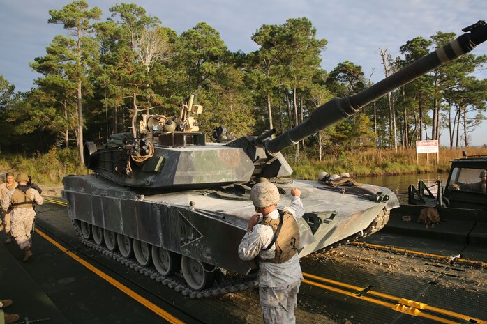 Cpl. Erikon C. Rosamond (center), a Kosciusko. Miss., native and combat engineer with Bridge Company, 8th Engineer Support Battalion, 2nd Marine Logistics Group, guides a M1A1A1 Abrams Main Battle Tank from 2nd Tank Battalion, 2nd Marine Division onto a raft made up of improved ribbon bridges during a tank crossing aboard Camp Lejeune, N.C., Oct. 17., 2013. The exercise offered the Marines a real life experience and took the tanks to Range SR-10, the only range sanctioned for the 120 mm cannon, for semi-annual qualification. (Photo by Lance Cpl. Shawn Valosin)