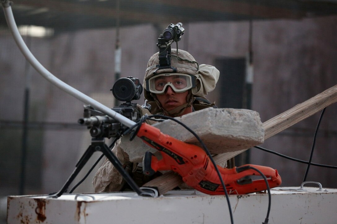 Lance Cpl. Paul Regotti, a rifleman with Animal Company, 1st Battalion, 7th Marine Regiment, and a native of Los Angeles, provides security with a M240B medium machine gun during a raid exercise here, Oct. 9, 2013. The Animal Co. Marines inserted into a training town by fast roping from UH-1Y Huey helicopters and engaged enemy role players while a designated team captured a suspected high-ranking insurgent. More than 20 Marines in the company were designated as enemy combatants and set up traps and obstacles throughout the town to challenge the assaulting Marines.