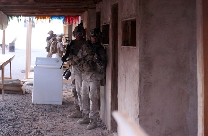 Marines with Animal Company, 1st Battalion, 7th Marine Regiment, prepare to enter a room with containing enemy role players during a raid exercise here, Oct. 9, 2013. The Animal Co. Marines inserted into a training town by fast roping from UH-1Y Huey helicopters and engaged enemy role players while a designated team captured a suspected high-ranking insurgent. The company conducted the raid as part of the Weapons and Tactics Instructor Course in preparation for their deployment to Afghanistan this spring.