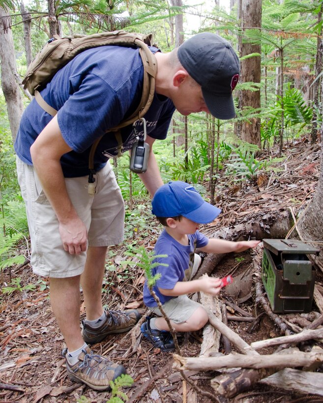 Maj. Doug Strahan, an operations planner with G-3, U.S. Marine Corps Forces, Pacific, and his son open one of the oldest geocaches hidden on Oahu, Oct. 12, 2013. Strahan said ammunition cans are good containers for geocaches. (U.S. Marine Corps photo by Kristen Wong)