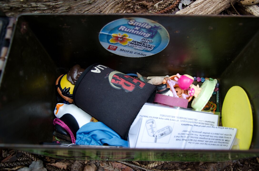 Geocaching enthusiasts place various objects in their caches. There is usually a log in which people can sign their name and the date they found the geocache. Sometimes there are "trackables" found in each geocache, that people take with them and send them on journeys to other geocaches. Some trackables have special codes that can be entered online. (U.S. Marine Corps photo by Kristen Wong)