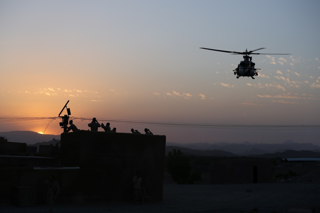 Marines with Animal Company, 1st Battalion, 7th Marine Regiment, watch as a UH-1Y Huey helicopter flies by during a raid exercise here, Oct. 9, 2013. The Animal Co. Marines inserted into a training town by fast roping from the helicopters and engaged enemy role players while a designated team captured a suspected high-ranking insurgent. More than 20 Marines in the company were designated as enemy combatants and set up traps and obstacles throughout the town to challenge the assaulting Marines.