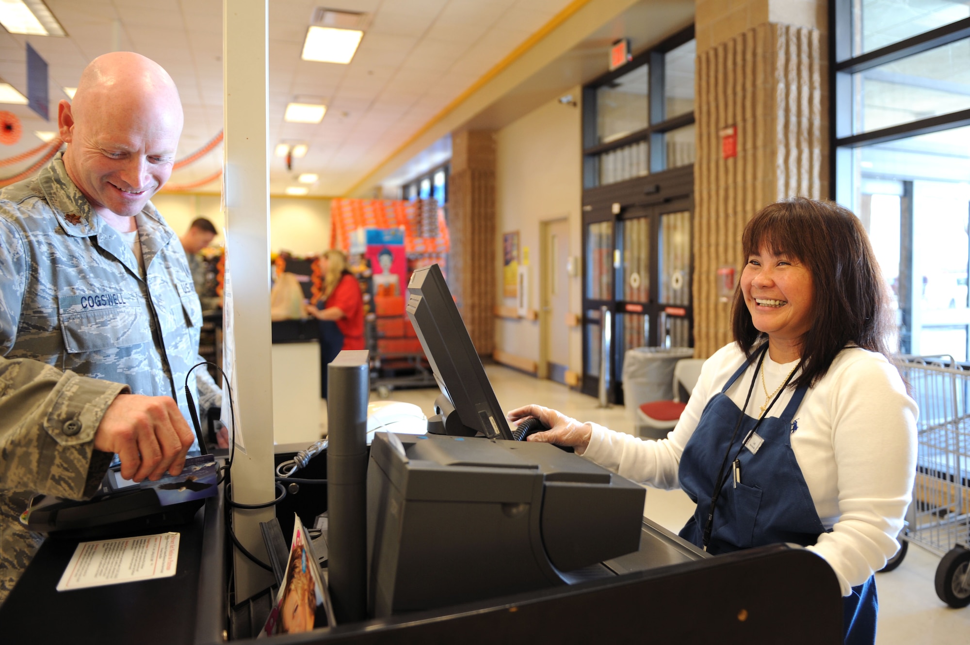 Luigi Fritz, base commissary cashier, rings up Maj. Bradley Cogswell, 12th Air Force Air Forces Southern, at the base commissary at Davis-Monthan Air Force Base, Ariz., Oct. 11, 2013. The base commissary is one of the many facilities that re-opened their doors after the civilian furlough recall Oct. 7, 2013. (U.S. Air Force photo by Airman 1st Class Saphfire Cook/Released) (cropped)