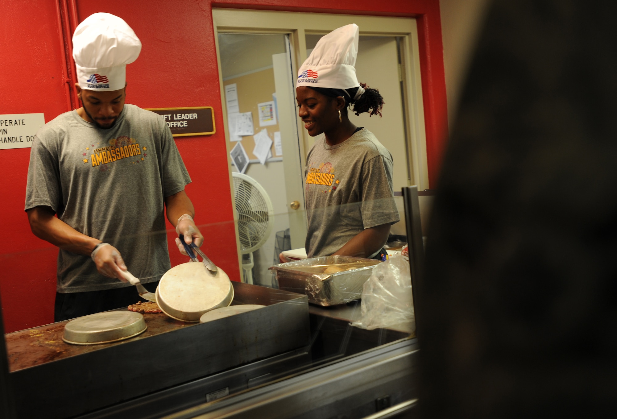 Marquette Knight and Inekka Stevenson, Harlem Ambassadors Basketball team members, help cook burgers during the Halloween themed Airmen Appreciation Meal at the Dakota Inn Dining Facility, Oct. 17. The team visited Minot Air Force Base, N.D., to take part in an exhibition game at the McAdoo Sports and Fitness Center. As part of their visit they showed their appreciation for U.S. military members by cooking for them. (U.S. Air Force photo/Senior Airman Jose L. Hernandez)