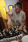 Tech. Sgt. Nicole Joy-Harris, 5th Force Support Squadron food service craftsman, cuts a cake that resembles a cemetery, during the Halloween themed Airmen Appreciation Meal at the Dakota Inn Dining Facility, Oct. 17. In the spirit of Halloween, chefs and shift leaders at the DFAC dressed in zombie-style costumes. (U.S. Air Force photo/Senior Airman Jose L. Hernandez)