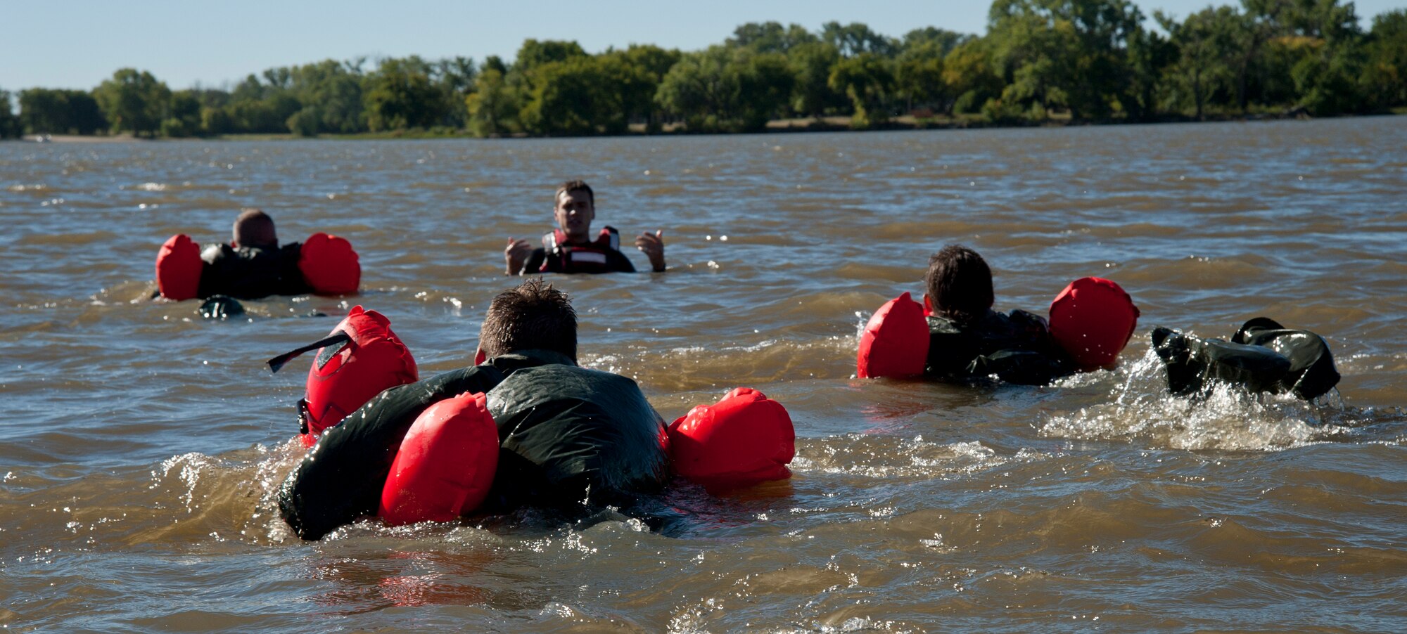 Airmen swim toward Staff Sgt. John Michels, 22nd Operations Support Squadron Survival, Evasion, Resistance and Escape specialist, during water survival training Oct. 8, 2013, in Augusta, Kan. This training covered egress procedures during emergency landings in water. (U.S. Air Force photo/Airman 1st Class Victor J. Caputo)