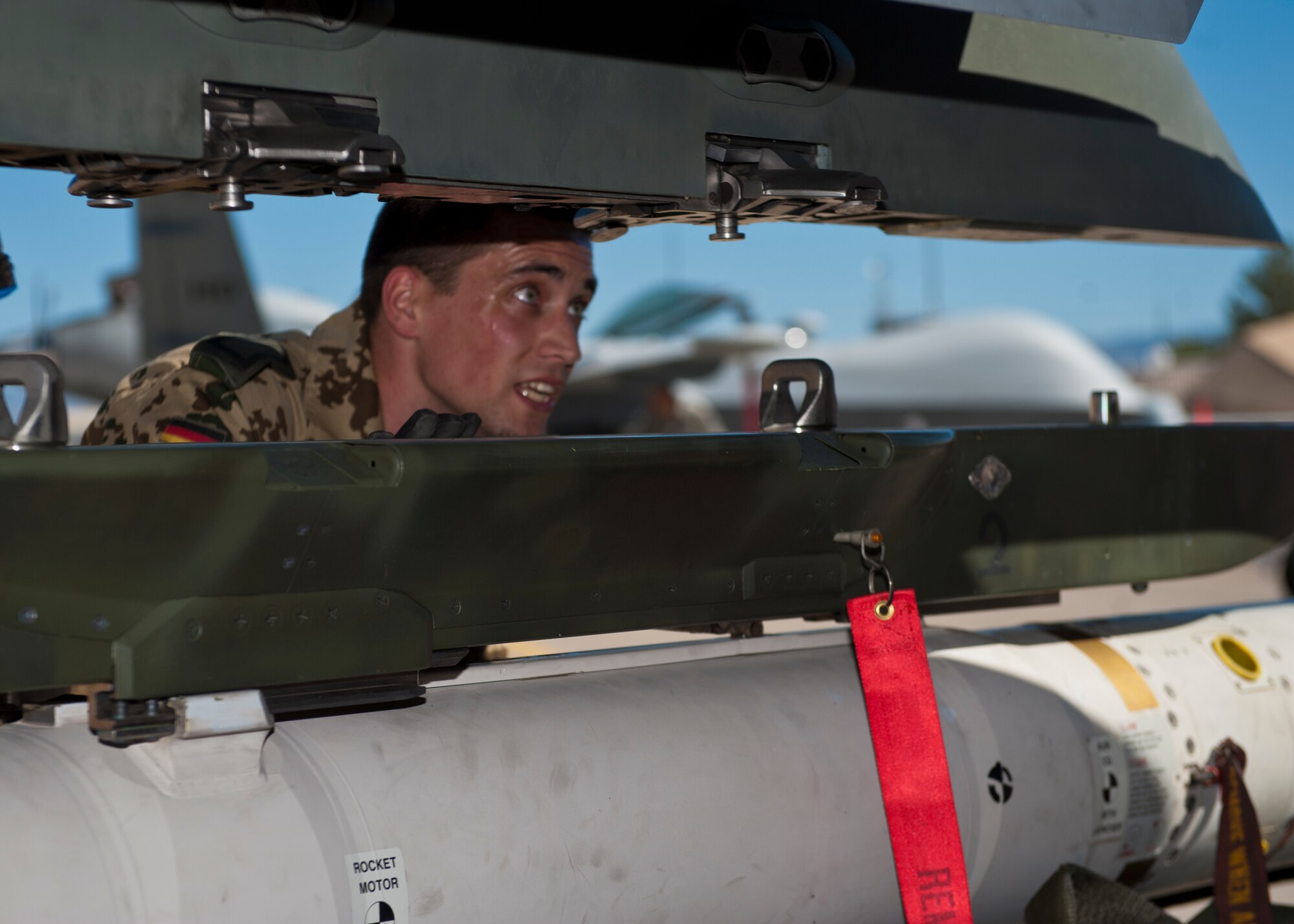German Air Force Staff Sgt. Daniel Schultes, German Air Force Flying Training Center weapons load crew member, aligns an inert missile during the quarterly load crew competition at Holloman Air Force Base, N.M., Oct. 11. The MQ-9 Reaper load crew competed to have their skills evaluated alongside the F-22 Raptor and German Air Force Tornado load crews. For the competition, points were awarded during the weapons loading, tool kit inspection and uniform inspection. (U.S. Air Force photo by Airman 1st Class Aaron Montoya/Released)