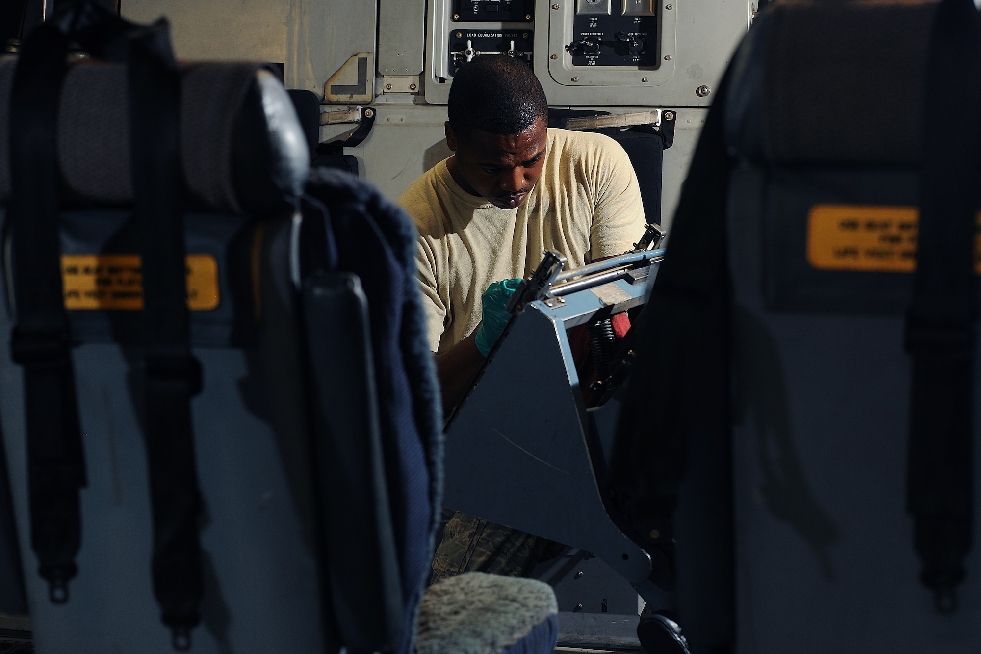 ALTUS AIR FORCE BASE, Okla. -- Senior Airman Brinson Emanuel, 97th Air Mobility Wing Maintenance Division crew chief, reconfigures the seats of a C-17 Globemaster III cargo aircraft during a 720-day home station refurbishing Oct. 10, 2013.  The recalibration of the seats helps to maintain the functionality of the seats’ components. The renovation ensures the workings of the aircraft are mission ready before returning to the field. (U.S. Air Force photo by Senior Airman Jesse Lopez/Released)