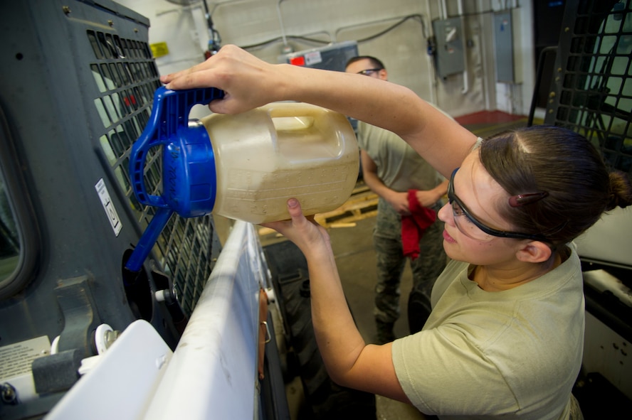 Airman 1st Class Johanna Desimone, 5th Logistics Readiness Squadron vehicle maintainer, pours fluid into a loader after checking the fluid level at Minot Air Force Base, N.D., Oct. 16, 2013. The 5th LRS vehicle maintenance flight repairs and maintains various types of vehicles to ensure Minot AFB stays mobile. (U.S. Air Force photo/Senior Airman Brittany Y. Auld)