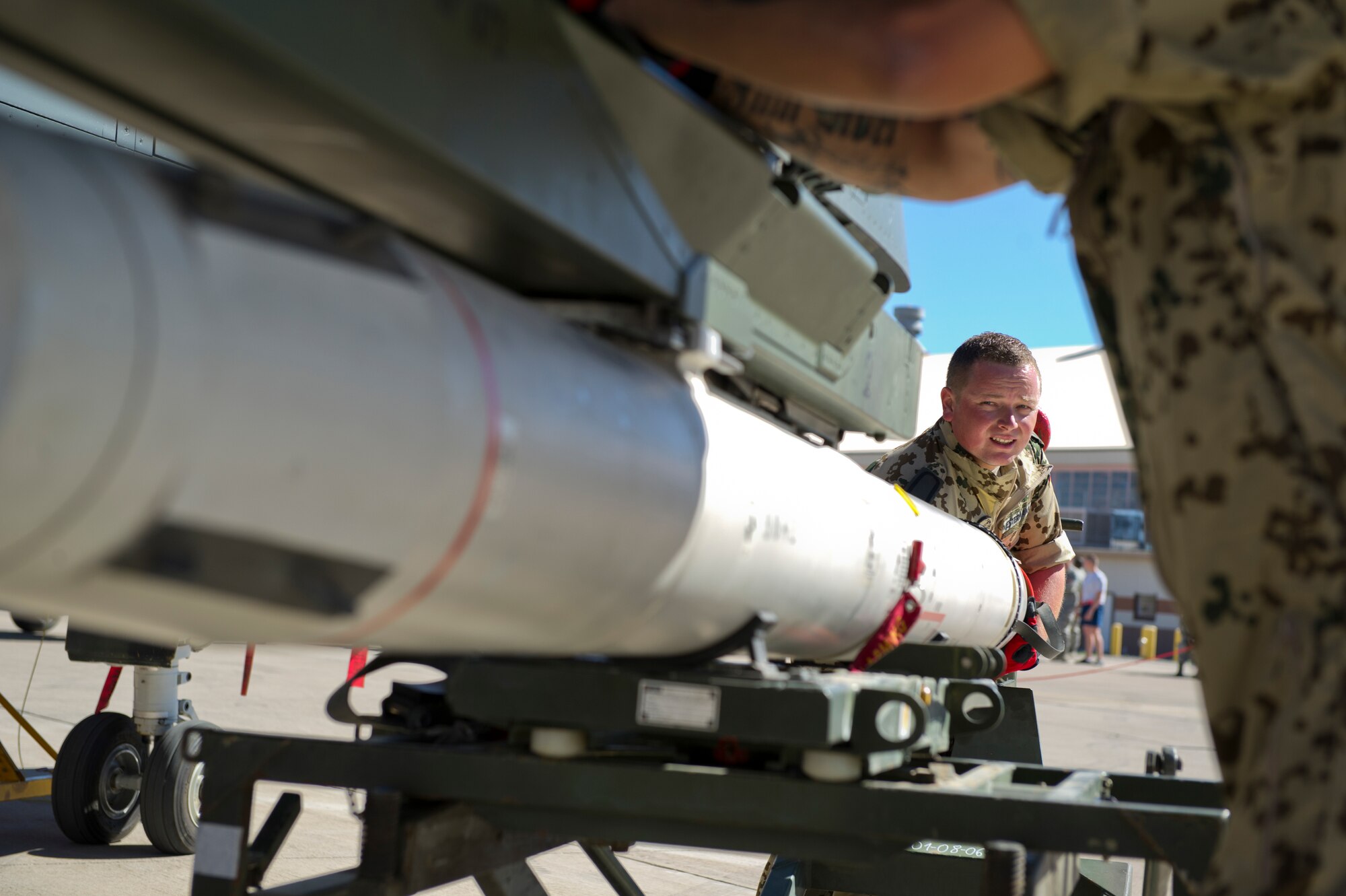 German Air Force Staff Sgt. Aleander Westermann, German Air Force Flying Training Center weapons load crew member, locks an inert missile onto the bottom of a Tornado aircraft during the quarterly load crew competition at Holloman Air Force Base, N.M., Oct 11. The German load crew competed to have their skills evaluated alongside U.S. Air Force F-22 Raptor and MQ-9 Reaper load crews. For the competition, points were awarded for weapons loading, tool kit inspection and uniform inspection. (U.S. Air Force photo by Airman 1st Class Chase Cannon/Released)