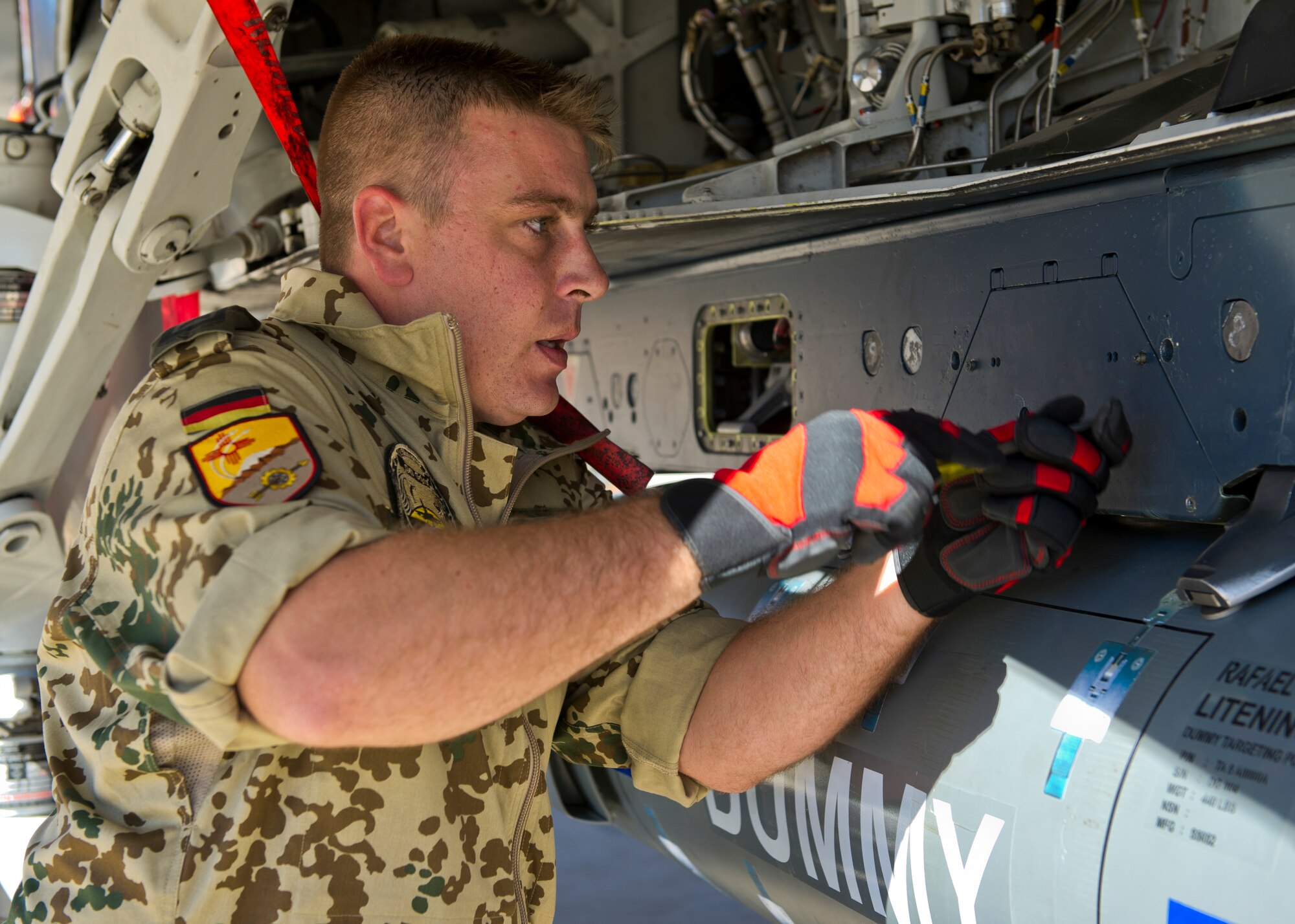 Tech. Sgt. Stefan Hoppe, German Air Force Flying Training Center weapons load crew member, locks an inert missile onto a Tornado aircraft during the quarterly load crew competition at Holloman Air Force Base, N.M., Oct 11. The German load crew competed to have their skills evaluated alongside U.S. Air Force F-22 Raptor and MQ-9 Reaper load crews. For the competition, points were awarded for weapons loading, tool kit inspection and uniform inspection. (U.S. Air Force photo by Airman 1st Class Chase Cannon/Released)