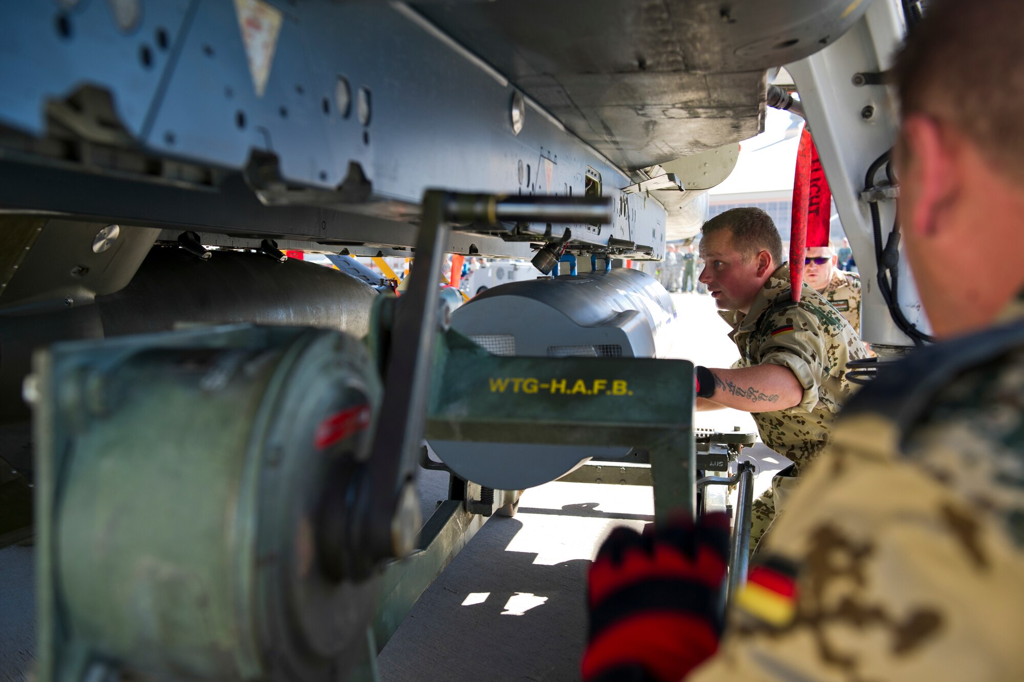 German Air Force Staff Sgt. Aleander Westermann and Tech. Sgt. Stefan Hoppe, German Air Force Flying Training Center weapons load crew members, lock an inert missile onto the bottom of a Tornado aircraft during the quarterly load crew competition at Holloman Air Force Base, N.M., Oct 11. The German load crew competed to have their skills evaluated alongside U.S. Air Force F-22 Raptor and MQ-9 Reaper load crews. For the competition, points were awarded for weapons loading, tool kit inspection and uniform inspection. (U.S. Air Force photo by Airman 1st Class Chase Cannon/Released)