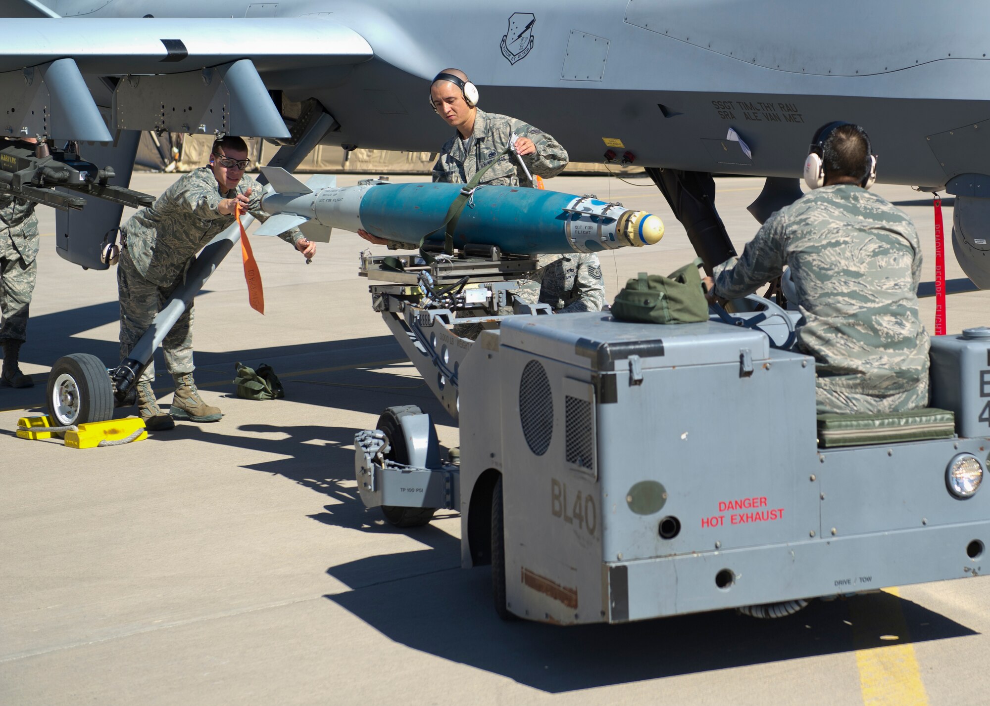 Senior Airman Binh Nguyen, Airman 1st Class Robert Lawrence and Staff Sgt. Jonathon Adams, members of the 849th Aircraft Maintenance Squadron weapons load crew, load an inert missile onto an MQ-9 Reaper aircraft during a quarterly load crew competition at Holloman Air Force Base, N.M., Oct 11. The MQ-9 Reaper load crew competed to have their skills evaluated alongside F-22 Raptor and the German Air Force Tornado load crews. For the competition, points were awarded for weapons loading, tool kit inspection and uniform inspection. (U.S. Air Force photo by Airman 1st Class Chase Cannon/Released)