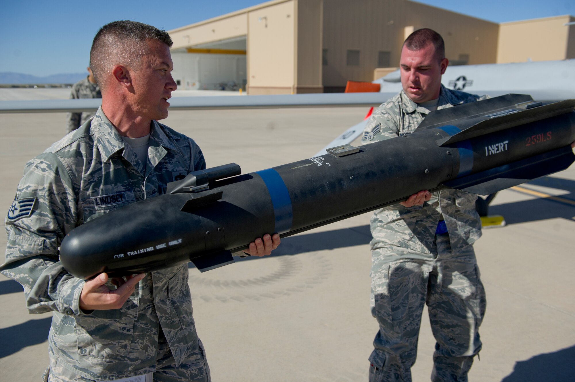 Staff Sgt. Timothy Lindsey and Senior Airman Michael Knowlton, both 849th Aircraft Maintenance Squadron weapons load crew members, prepare to load an inert missile during a quarterly load crew competition at Holloman Air Force Base, N.M., Oct. 11. The 849th AMXS pitted two MQ-1 Predator aircraft load crews against each other to evaluate who could prepare the aircraft for combat the quickest and with the fewest procedural errors. (U.S. Air Force photo by Airman 1st Class Chase Cannon/Released)
