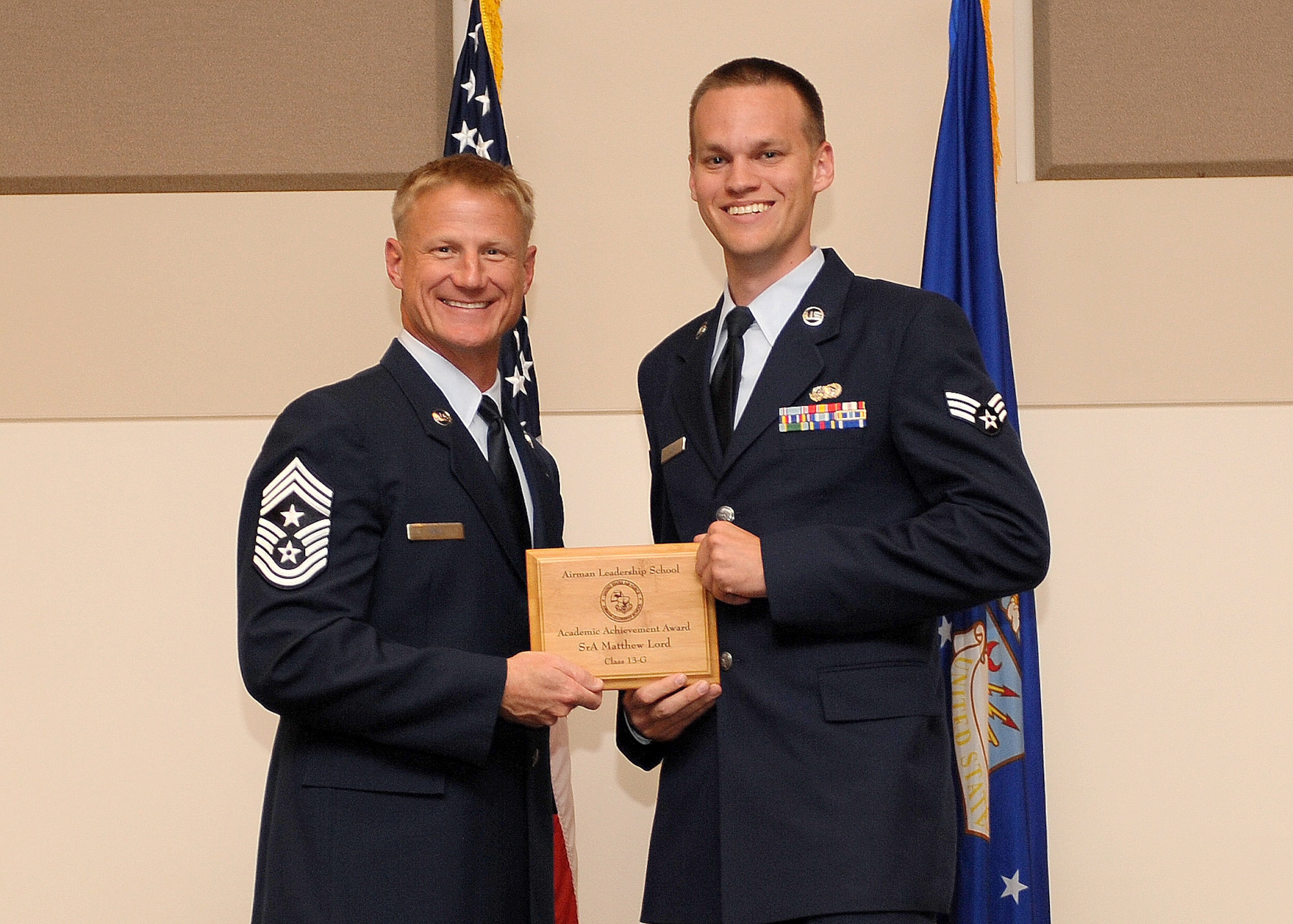 Senior Airman Matthew Lord, 460th Space Communications Squadron, right, receives the Academic Achievement Award during the Buckley Airman Leadership School Class 13-F graduation Oct. 17, 2013, at the Leadership Development Center on Buckley Air Force Base, Colo. The academic award is given to the student with the highest overall average score on all academic evaluations during ALS. (U.S. Air Force photo by Senior Airman Marcy Copeland/Released)