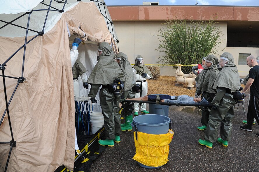 Members of the 56th Medical Operations Squadron carry a patient to the decontamination tent Oct. 10 during a decontamination exercise at Luke Air Force Base. The automated tent rinses simulated contaminants from patients. The 56th MDOS conducts exercises every other month throughout the year to ensure they are ready for real-world emergencies. (U.S. Air Force photo/Airman 1st Class James Hensley)