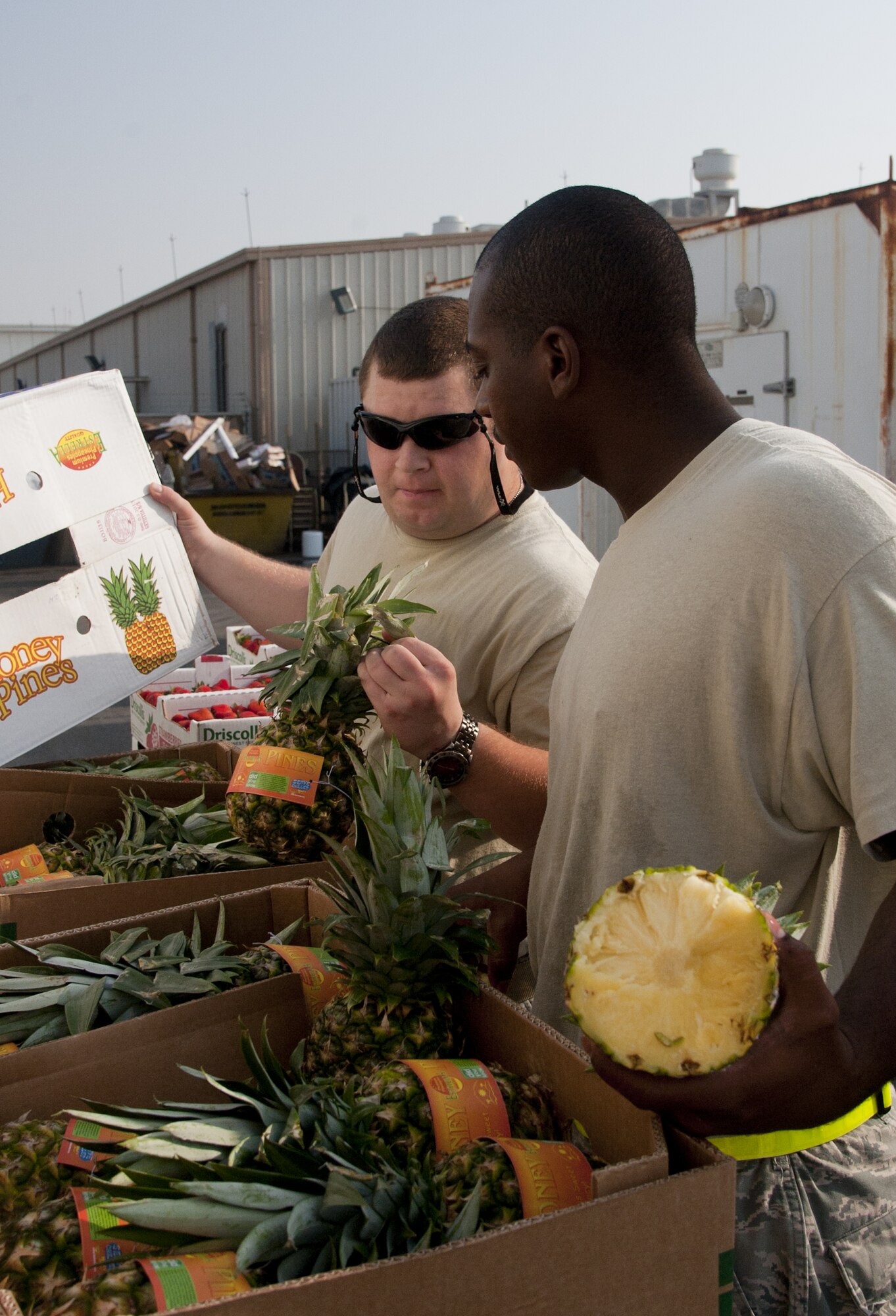 U.S. Air Force Staff Sgt. Luke Hammond, 380th Expeditionary Force Support Squadron, left, and U.S. Air Force Staff Sgt. Jemar Battle, 380th EFSS, inspect pineapples upon delivery at an undisclosed location in Southwest Asia Oct. 8, 2013. Hammond and Battle were part of a large EFSS team, who all come together to stock food when it is delivered. Hammond and Battle are both deployed from Nellis Air Force Base, Nev. (U.S. Air Force photo by Staff Sgt. Jacob Morgan)
