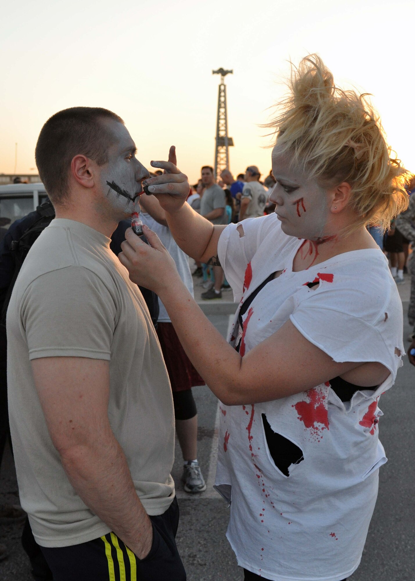 Airman 1st Class Rebecca Yohn applies moulage to Senior Airman Andrew Hardcastle in preparation for a zombie run at the 379th Air Expeditionary Wing in Southwest Asia, Oct. 12, 2013. The run was hosted by the Rising Six private organization to boost the morale of individuals on the base. Yohn is an 8th Expeditionary Air Mobility Squadron air transportation specialist deployed from Ramstein Air Base, Germany, and a St. Louis native. Hardcastle is a 71st Expeditionary Air Control Squadron radio frequency transmissions apprentice deployed from Spangdahlem AB, Germany, and a Seattle native. (U.S. Air Force photo/1st Lt. Susan Harrington)