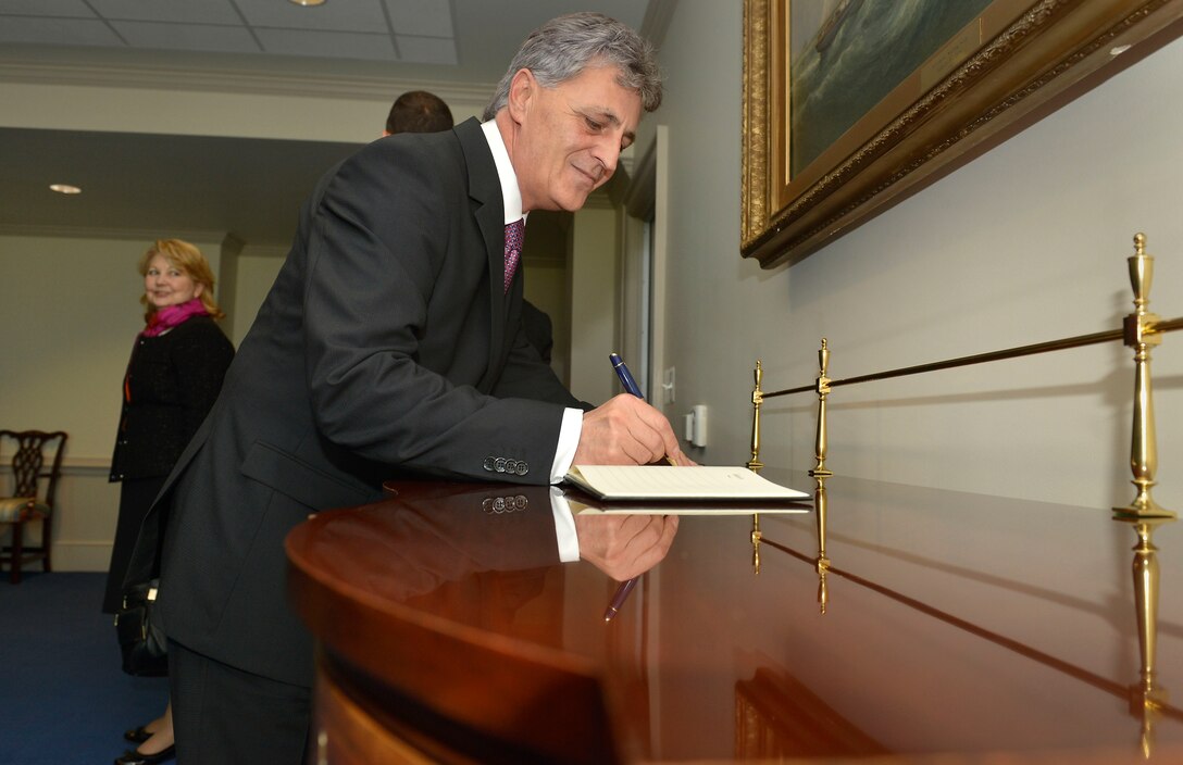 Romania's Defense Minister Mircea Dusa signs the guestbook before joining U.S. Defense Secretary Chuck Hagel for a meeting at the Pentagon, Oct. 18, 2013.
