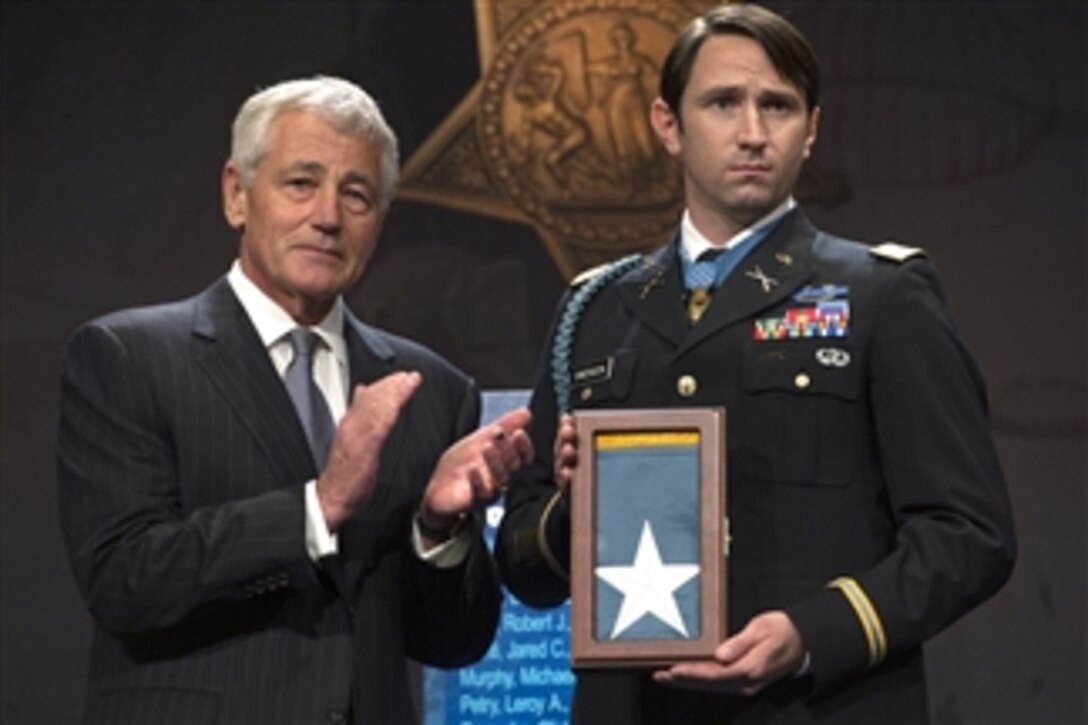Secretary of Defense Chuck Hagel, left, applauds after presenting the Medal of Honor flag to former Army Capt. William Swenson during his induction into the Pentagon Hall Of Heroes in Arlington, Va., on Oct. 16, 2013.  Swenson is the first Army officer to receive the Medal of Honor for actions in Iraq or Afghanistan.  