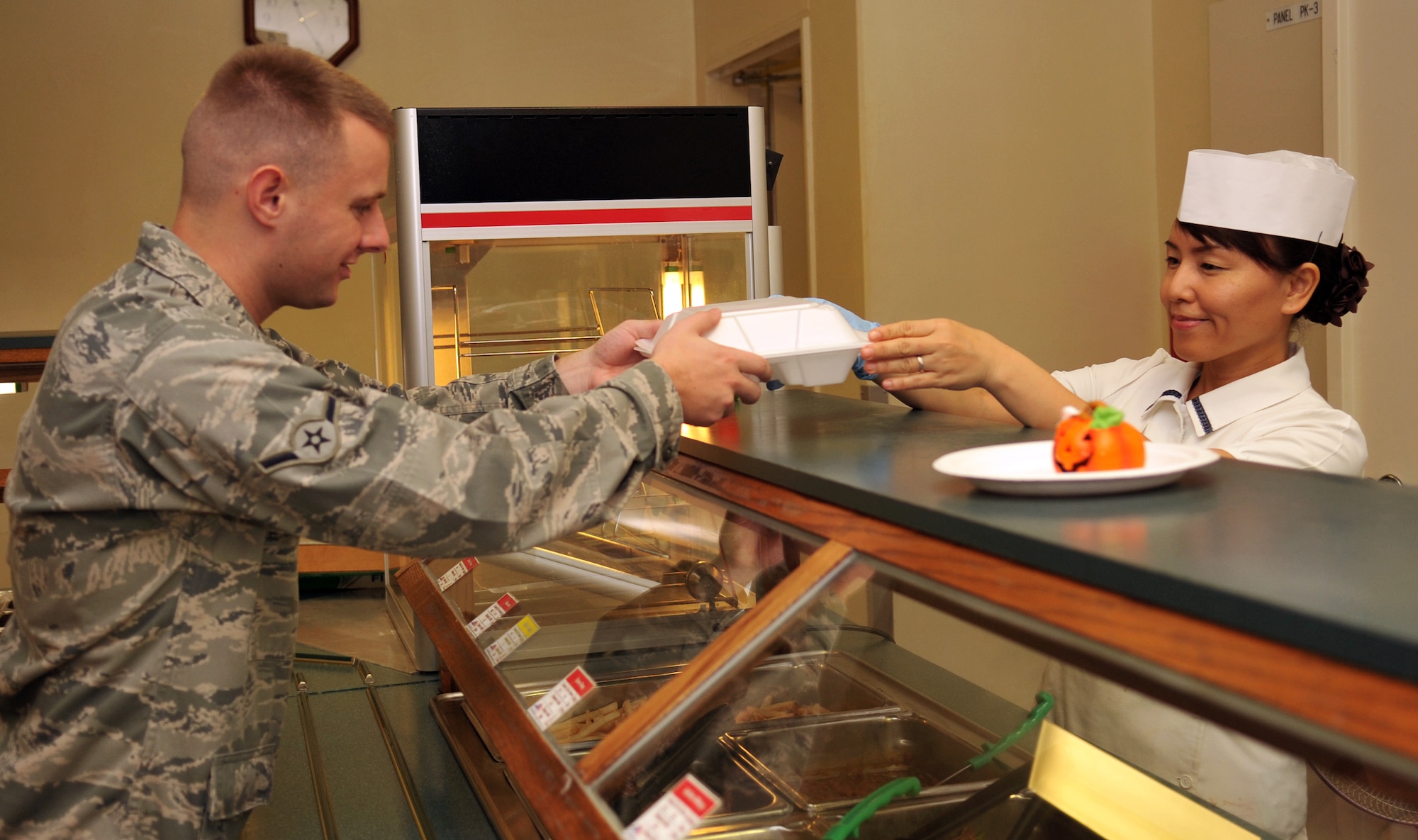 Kisako Yagi, 18th Force Support Squadron mess attendant, serves a plate to an airman during lunch at the Marshall Dining Facility on Kadena Air Base, Japan, Oct. 17, 2013. The Marshall Dining Facility serves an average of 1,200 people daily. (U.S. Air Force photo by Naoto Anazawa)