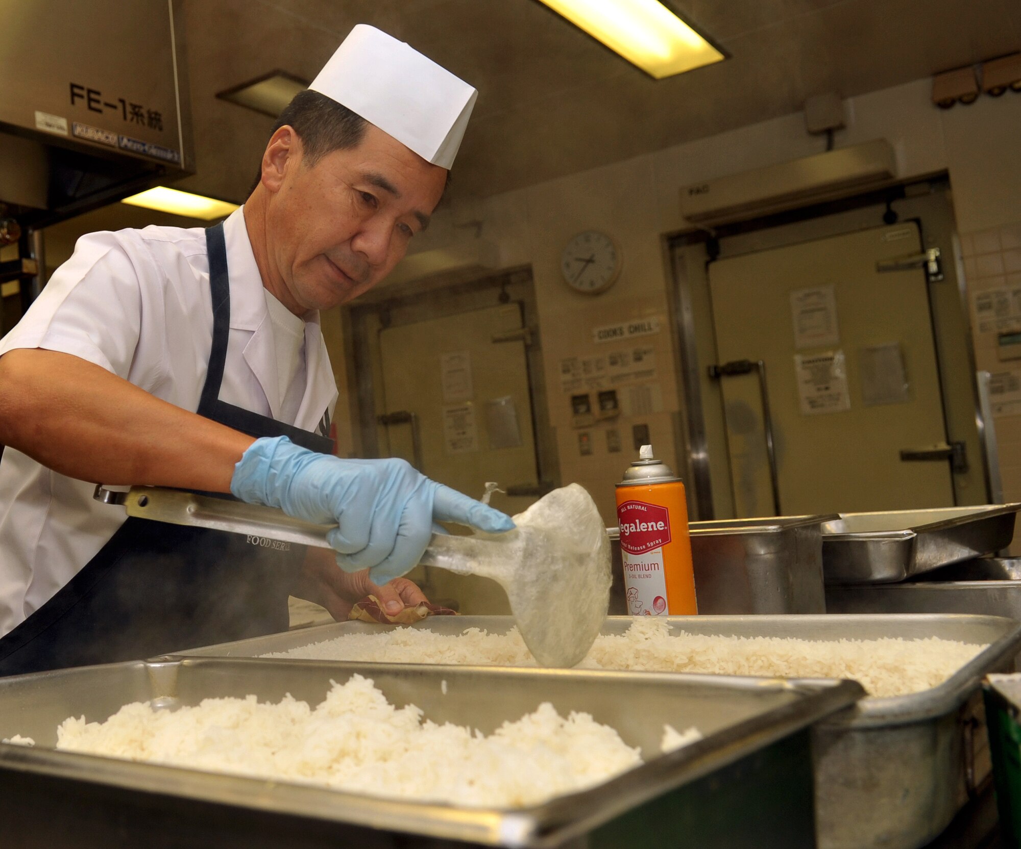 Riki Yokoda, 18th Force Support Squadron cook, combines two pans of rice for lunch at the Marshall Dining Facility on Kadena Air Base, Japan, Oct. 17, 2013. Members of the Marshall Dining Facility begin preparing meals about an hour before the first customer is served. (U.S. Air Force photo by Naoto Anazawa)

