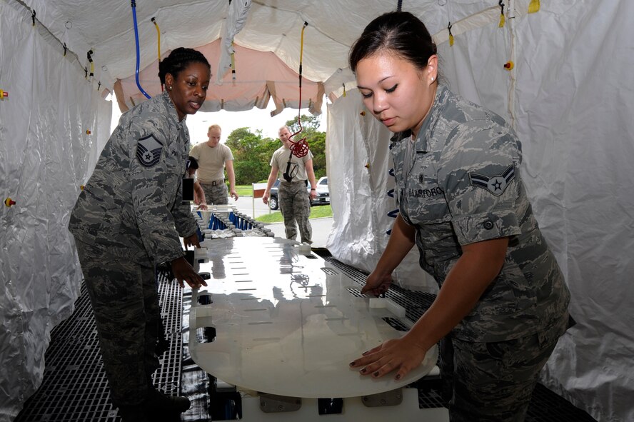 Master Sgt. Geisha Patton, 18th Medical Support Squadron in-place patient decontamination team chief, and Airman 1st Class Tiffany Speth, 18th Medical Operations Squadron medical technician, set up a decontamination tent for training at Kadena Air Base, Japan, Oct. 17, 2013. The tent is used to treat patients who have been contaminated by a chemical attack. (U.S. Air Force photo by Senior Airman Marcus Morris) 
