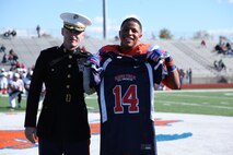Maj. Gregory P. Gordon, the Commanding Officer of Recruiting Station St. Louis, presents a Semper Fidelis All-American Bowl jersey to high school senior Kyron Watson during a football game in East St. Louis, Ill., Oct. 19, 2013. Watson was selected to participate in the Semper Fidelis All-American Bowl in January in Carson, Calif. Watson plays Linebacker on the East St. Louis Senior High School varsity football team and is ranked a four-star recruit and 105th in the ESPN top 300. He has had 10 scholarship offers, but committed to play at the University of Kansas. (Official U.S. Marine Photo by Cpl. Erik S. Brooks Jr.)