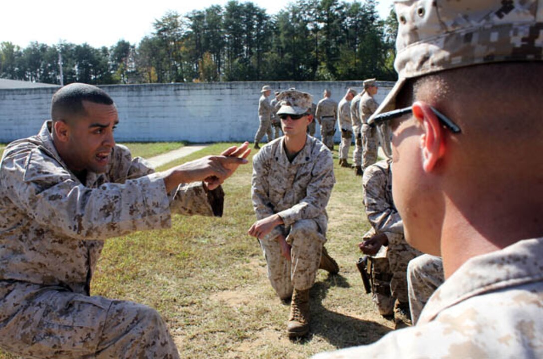 Cpl. Ambrose Bandy (left), marksmanship instructor for Marksmanship Training Co., Weapons Training Battalion, demonstrates correct form when firing a pistol, during a quick impromptu lesson with Marines who are qualifying at the pistol range aboard Marine Corps Base Quantico. Non-commissioned officers like Bandy are considered the “backbone” of the Marine Corps and are a key component in the commandants plan to bolster leadership and commitment to building Marines who embody the Corps’ ethos and values.