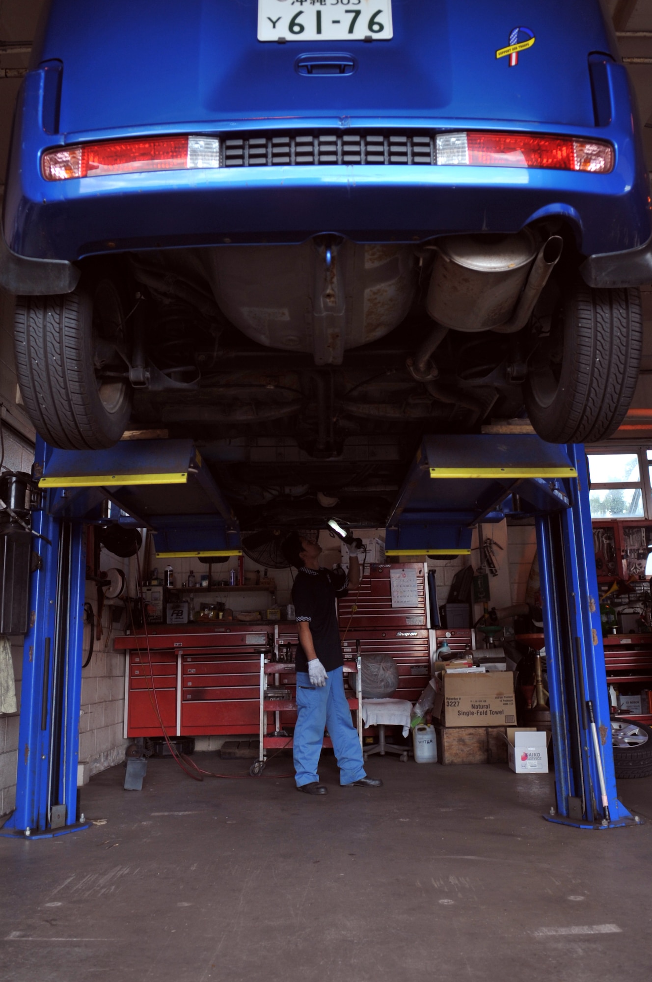 Atsushi Takara, auto hobby center mechanic, inspects the underside of a car at the auto hobby center on Kadena Air Base, Japan, Oct. 21, 2013. The auto hobby center rents garage space for a nominal fee and car experts will give advice or assistance during the repair. (U.S. Air Force photo by Naoto Anazawa)