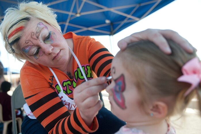 Holly Keller, 99th Force Support Squadron Squadron Child Development Center services intern, paints a child's face during the annual Harvest Festival held at the CDC Oct. 19, 2013, at Nellis Air Force Base, Nev. In addition to face painting, children were also able to play games, participate in a costume parade, and compete in a cakewalk. (U.S. Air Force photo by Staff Sgt. Christopher Hubenthal)