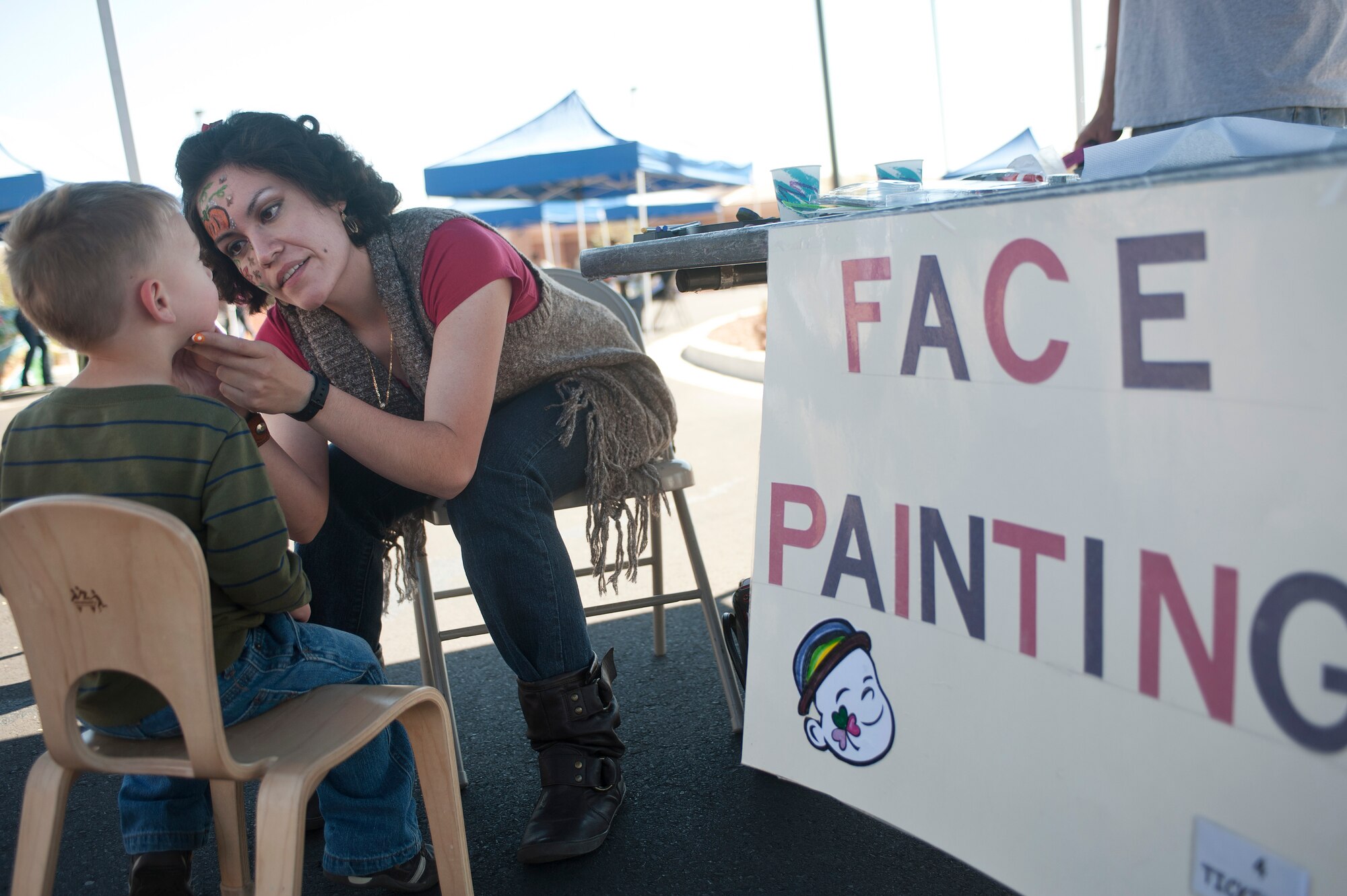Airman 1st Class Emily Vega, 757th Aircraft Maintenance Squadron Thunder Aircraft Maintenance Unit aircraft armament systems apprentice, paints a child's face during the annual Harvest Festival held at the Child Development Center Oct. 19, 2013, at Nellis Air Force Base, Nev.  In addition to face painting, children were also able to play games participate in a costume parade, and compete in a cakewalk. (U.S. Air Force photo by Staff Sgt. Christopher Hubenthal)