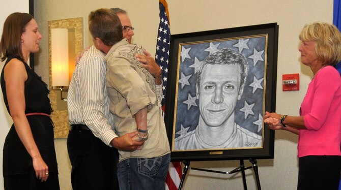 Peter Servais (left) hugs artist Phil Taylor as his daughter, Laura, and wife, Susan, look on after the unveiling of the portrait in honor of his son, Senior Airman Adam Servais Oct. 19, 2013, in Destin, Fla.  Servais, a 23rd Special Tactics Squadron combat controller, was killed in action Aug. 19, 2006 while deployed to Afghanistan. (U.S. Air Force photo by Capt. Victoria Porto)