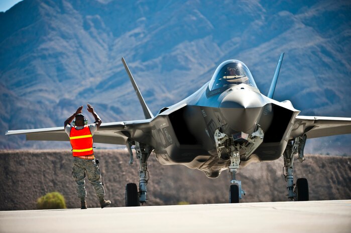 Tech. Sgt. Jermaine Lee, 57th Aircraft Maintenance Squadron aerospace propulsion specialist, marshals an F-35 Lightning II at the revetments Oct. 16, 2013, at Nellis Air Force Base, Nev. The 57th AMXS Lightning Aircraft Maintenance Unit conducted for the first time, back-to-back training missions utilizing hot-pit refueling, a procedure usually performed in a combat situation to rapidly refuel aircraft while their engines are running, resulting in a speedy refuel and getting pilots right back into the fight. (U.S. Air Force photo by Senior Airman Brett Clashman)