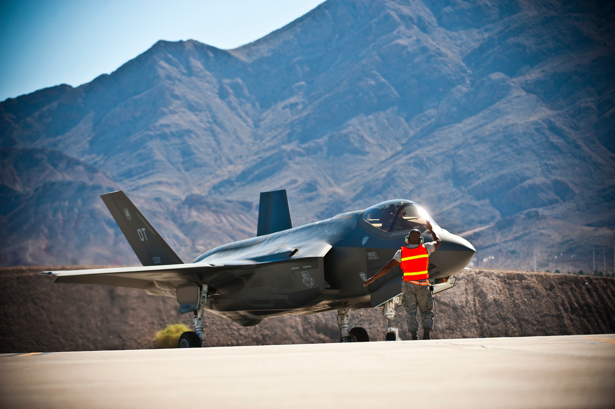 Tech. Sgt. Jermaine Lee, 57th Aircraft Maintenance Squadron aerospace propulsion specialist, marshals an F-35 Lightning II at the revetments Oct. 16, 2013, at Nellis Air Force Base, Nev. The 57th AMXS Lightning Aircraft Maintenance Unit conducted for the first time, back-to-back training missions utilizing hot-pit refueling, a procedure usually performed in a combat situation to rapidly refuel aircraft while their engines are running, resulting in a speedy refuel and getting pilots right back into the fight. (U.S. Air Force photo by Senior Airman Brett Clashman)