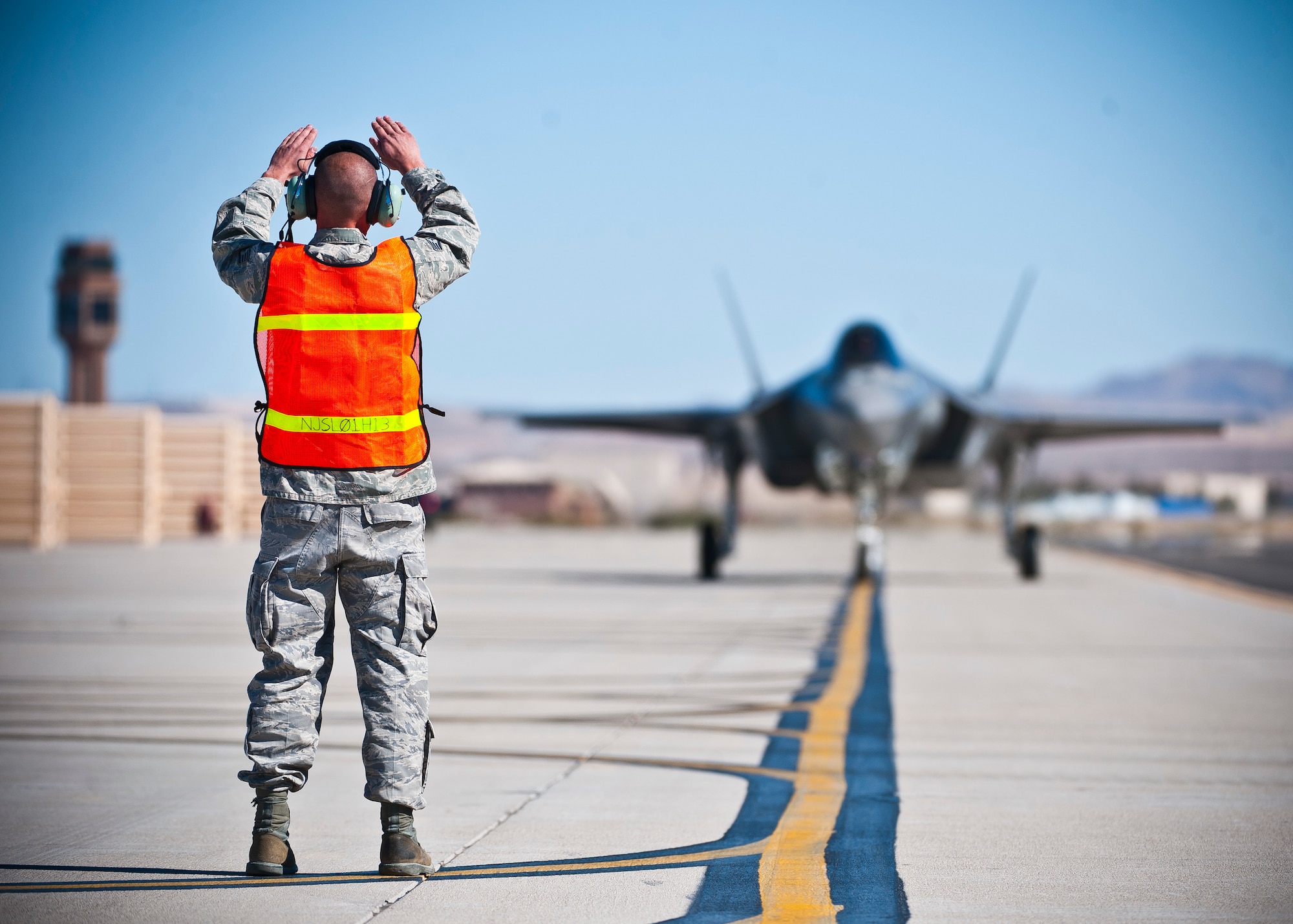 Staff Sgt. William Rispoli, 57th Aircraft Maintenance Squadron aerospace propulsion specialist, marshals an F-35 Lightning II at the revetments Oct. 16, 2013, at Nellis Air Force Base, Nev. The F-35 is a single-seat, single-engine, fifth-generation multirole fighter that performs ground attack, reconnaissance, and air defense missions with stealth capability. (U.S. Air Force photo by Senior Airman Brett Clashman)