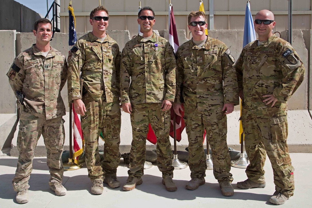 U.S. Air Force Tech. Sgt. James Juniper (center), NATO Air Training Command-Afghanistan special mission aviator advisor, received the Purple Heart October 10, 2013 at Kandahar Airfield, Afghanistan, for wounds sustained during a Mi-17 helicopter mission near Gizab, Afghanistan. He poses at the ceremony with the other members of the October 8, 2013 mission who helped to save his life; Capt. Jeremy Powell (left), NATC-A Mi-17 pilot advisor, Staff Sgt. Mark Cornett, Staff Sgt. Ben Jacobs and Staff Sgt. Chris Rector, NATC-A SMA advisors. (U.S. Air Force photo)