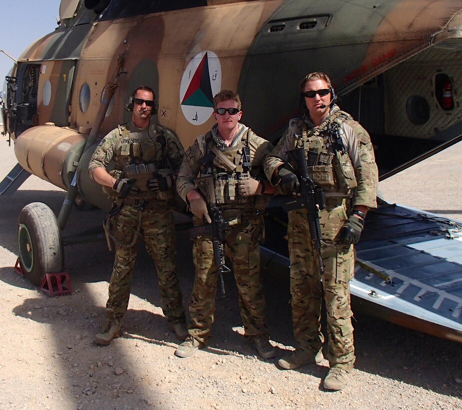 U.S. Air Force Tech. Sgt. James Juniper (left), Staff Sgt. Ben Jacobs and Staff Sgt. Mark Cornett, NATO Air Training Command-Afghanistan special mission aviator advisors, pose for a photo while their Mi-17 helicopter is refueled at Tarin Khowt Airfield, Afghanistan. Just moments after this photo was taken the crew took-off on the mission that would cause Juniper to be awarded the Purple Heart. The October 8, 2013 mission was a troop movement mission transporting Afghan National Army commandos from Tarin Khowt Airfield in Uruzgan Province to the district of Gizab. The helicopter was engaged by small arms fire and rocket propelled grenades from multiple locations. (U.S. Air Force photo)