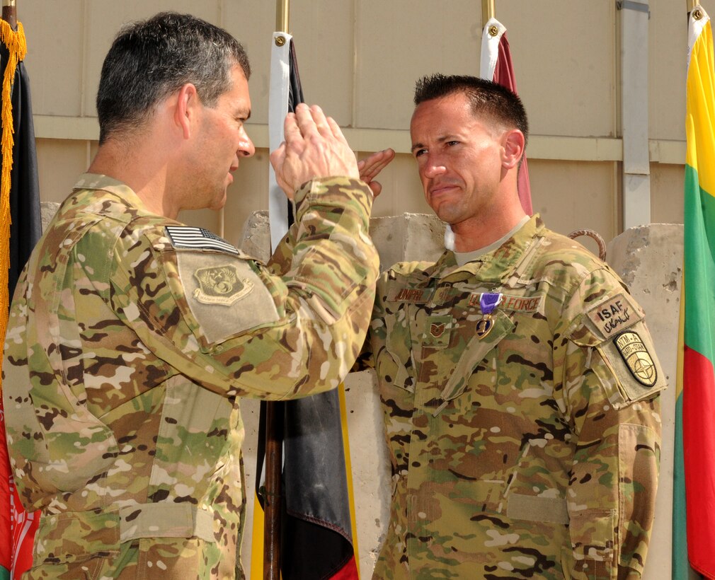 U.S. Air Force Tech. Sgt. James Juniper, NATO Air Training Command-Afghanistan special mission aviator advisor, is awarded the Purple Heart by Maj. Gen. Kenneth Wilsbach, 9th Air and Space Expeditionary Task Force commander, during at ceremony October 10, 2013 at Kandahar Airfield, Afghanistan. Juniper was awarded the Purple Heart for wounds sustained during a Mi-17 helicopter mission October 8, 2013 near Gizab, Afghanistan. (U.S. Air Force photo/Senior Airman Jack Sanders)