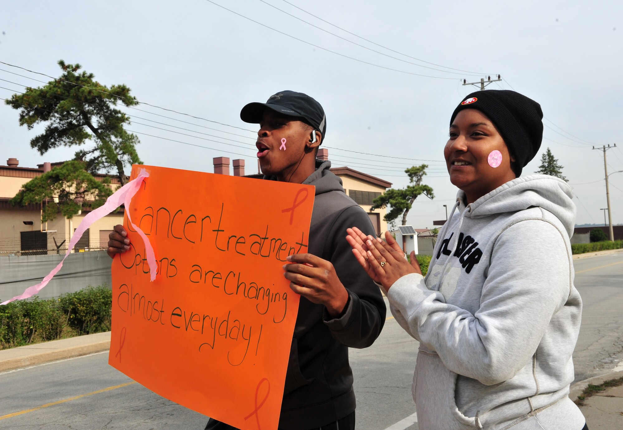 Airman 1st Class Yontaireus McCoy, and Senior Airman Vaniece Moore, 51st Force Support Squadron lodging front desk representatives, cheer on runners during a Breast Cancer and Domestic Violence Awareness 5K at Osan Air Base, Republic of Korea, Oct. 19, 2013. Out of approximately 167 runners, many finished in less than 30 minutes. (U.S. Air Force photo/Airman 1st Class Ashley J. Thum)