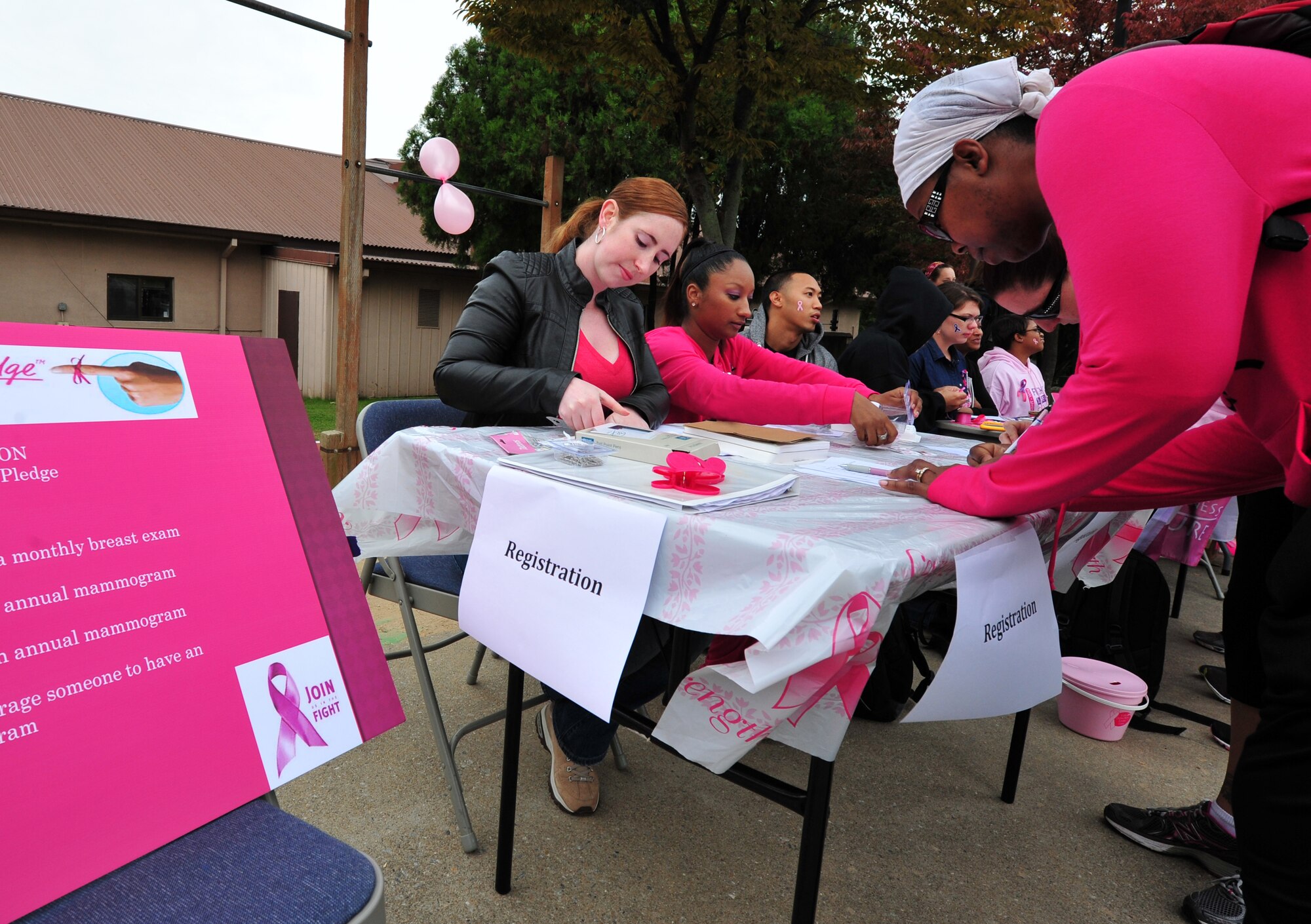 Staff Sgt. Kathryn Bowman, 7th Air Force command chief executive assistant, assists a Breast Cancer and Domestic Violence Awareness 5K participant with registration at Osan Air Base, Republic of Korea, Oct. 19, 2013. The 5K was one of many events hosted by the Breast Cancer and Domestic Violence Awareness committee throughout October. (U.S. Air Force photo/Airman 1st Class Ashley J. Thum)