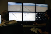 A Marine with 2nd Medical Battalion, Combat Logistics Regiment 25, 2nd Marine Logistics Group observes the performance of service members going through a virtual convoy at the Lockheed Martin Combat Convoy Simulator aboard Camp Lejeune, N.C., Oct. 18, 2013. Marines used stationary vehicle bodies (High Mobility Multipurpose Wheeled Vehicles or Medium Tactical Vehicle Replacements) and large projection screens that displayed computer-controlled terrain. 
