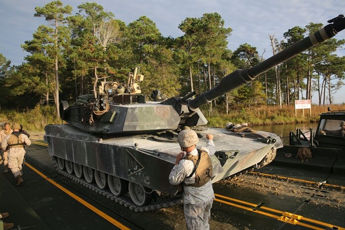 Cpl. Erikon Rosamond (center), a Kosciusko. Miss., native and combat engineer with Bridge Company, 8th Engineer Support Battalion, 2nd Marine Logistics Group, guides an M1A1A1 Abrams Main Battle Tank from 2nd Tank Battalion, 2nd Marine Division onto a raft made up of improved ribbon bridges during a tank crossing aboard Camp Lejeune, N.C., Oct. 17. The tank is just one of many pieces of equipment that can benefit from predictive analysis programs carried out through the Research and Readiness Analysis cell within Marine Corps Systems Command’s Acquisition Logistics and Product Support. 